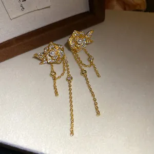 Close-up of elegant gold-plated rose earrings with pearls, zircons, and long tassels