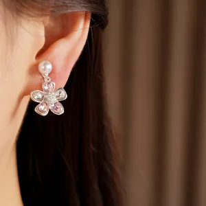 Dettaglio di orecchini a clip a fiore con cristalli rosa e perle bianche sulla modella