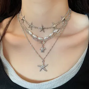 Detailed view of ocean-themed layered necklace with starfish, turtle pendants and pearls.