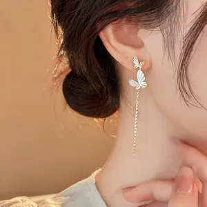 Close-up of elegant butterfly tassel earrings with sparkling crystals and white wings