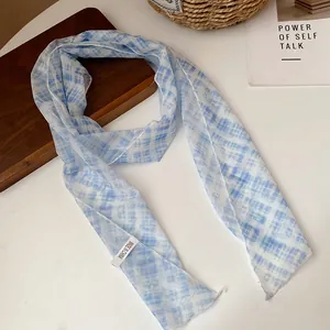 Close-up of a pastoral blue and white checkered mesh scarf necklace on a white wooden table