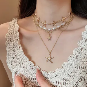 Close-up of gold layered necklace featuring starfish and turtle pendants on model neck