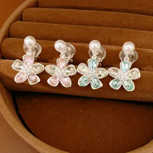 Dettaglio di quattro paia di orecchini a clip con fiori e perle in vassoio di velluto.