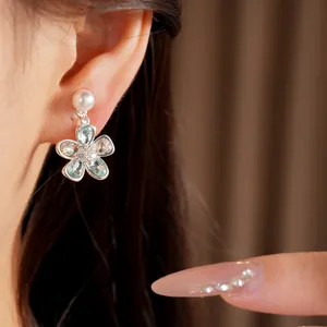 Primo piano di un elegante orecchino a clip a fiore con perla e pietre preziose blu