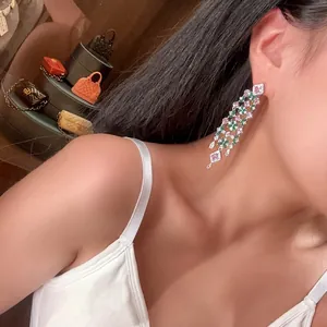 Detail view of sparkling zircon flower drop earrings with pink and green stones