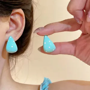 Detalle de pendientes esmaltados con lunares azul menta lucidos por una modelo real