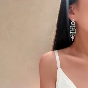 Elegant long floral dangle earrings with green and pink zircons shown on model