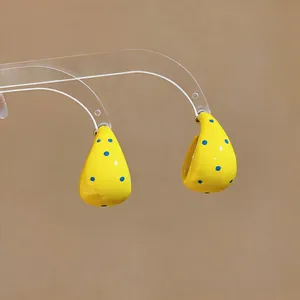 Primer plano de pendientes de aro amarillos en forma de C con motas azules