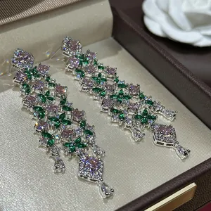 Detail view of sparkly pink and green zircon flower drop earrings in a jewelry box