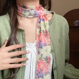 Detailed macro view of an elegant floral print mesh scarf necklace paired with a green cardigan