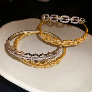 Elegant 18K gold plated zircon hollow buckle bracelets displayed on a ceramic jewelry plate