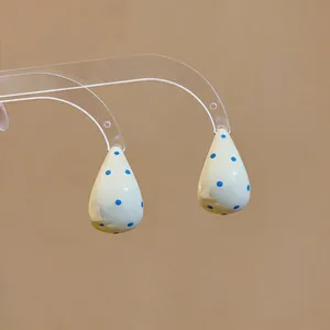 Primer plano detallado de elegantes pendientes de esmalte en forma de gota con lunares azules