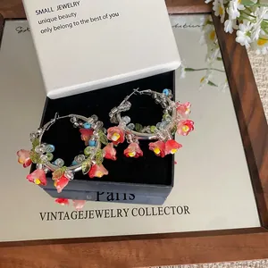 Dettaglio di orecchini a cerchio con fiori di perline rosa e petali in resina trasparente