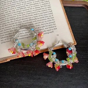 Primo piano di orecchini a cerchio con perline colorate e ciondoli a fiore su un libro