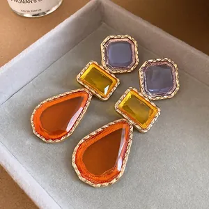 Gros plan de boucles d'oreilles pendantes vintage en résine multicolore dans un plateau gris