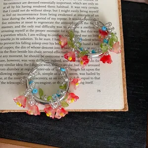 Vista macro di graziosi orecchini a cerchio con fiori di perline su un libro aperto