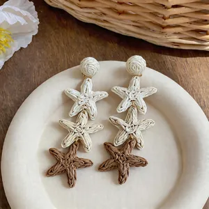 Handmade raffia woven star tassel earrings featuring a bohemian summer holiday design
