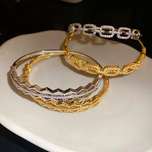 Detail view of 18K gold plated bracelets with micro-pave zircons on a white plate.