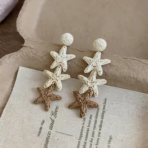 Close-up macro detail of handmade woven raffia star tassel earrings for summer vacation