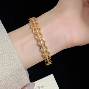 Detailed view of elegant gold-plated honeycomb bangle with zircons on a lady's wrist
