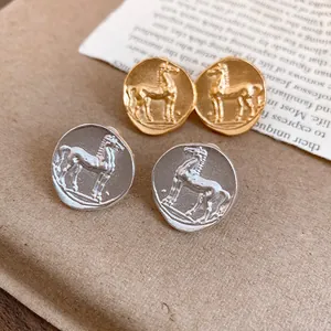 Close-up detail of vintage matte round stud earrings with horse pattern in gold and silver finish