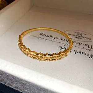 Detail shot of an 18K gold-plated bangle with a hollow geometric design and zircons