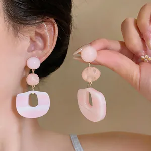 Nahaufnahme von rosa Acetat-Ohrringen mit geometrischem hohlem Tropfendesign