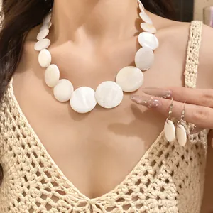 Close-up of elegant white shell disc necklace and matching hook earrings on model