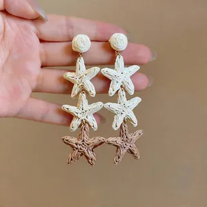 Handcrafted woven raffia star drop earrings in cream and tan colors for summer vacation