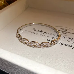 Detail shot of a silver-toned 18K gold-plated bangle with square pavé-set zircon links