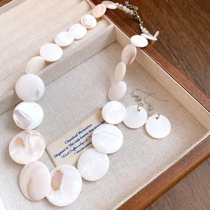 Detailed close-up of vintage shell disc necklace and matching earrings in a jewelry box