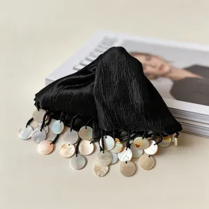 Detail view of black textured hair claw clip with iridescent shell tassel fringe