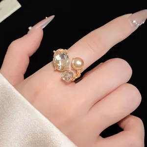 Elegant vintage gold open ring featuring an oval crystal and champagne pearl on finger