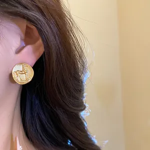 Detailed close-up of matte gold round stud earring with vintage embossed horse design