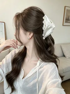 Elegant white pleated hair claw clip with delicate shell details on model's ponytail