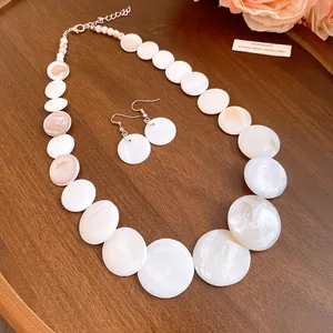 Close-up of elegant white circular shell pendant necklace and matching earrings set