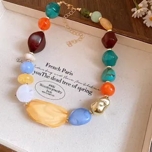 Detail view of colorful irregular acrylic beads on a gold-tone chain in a display box.