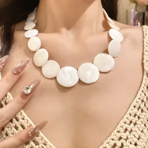 Close-up of elegant large white round shell necklace worn on model's neck