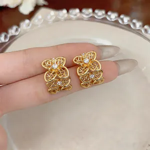 Gros plan détaillé de boucles d'oreilles fleurs ajourées vintage dorées avec cristaux