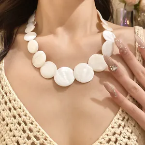 Detailed shot of retro white shell round disc necklace on model's neck with knit top