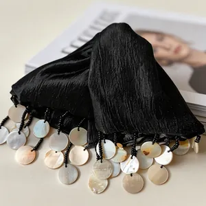 Macro detail of black pleated hair claw clip with iridescent shell disk tassels decoration
