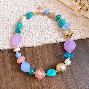 Close-up of colorful irregular acrylic beads on a Bohemian style necklace with gold accents.