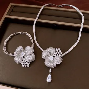 Elegant silver necklace and bracelet set with zirconia flower and teardrop pendants.
