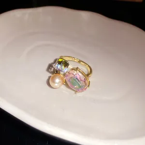 Detailed macro view of vintage open ring with pink oval crystal and pearl on white ceramic