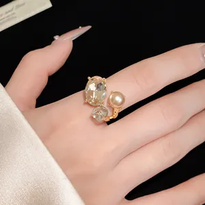 Close-up detail of elegant vintage gold open ring with oval crystal and pearl on finger