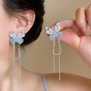 Elegante Schmetterlings-Quastenohrringe mit Silbernadeln in einer Nahaufnahme-Detailansicht.