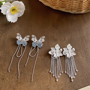 Nahaufnahme von Schmetterlings- und Blumenohrringen mit Quasten auf einer Holzoberfläche