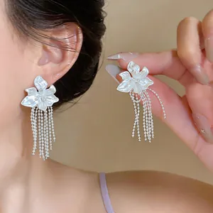 Detailansicht eleganter weißer Blumenohrstecker mit langen silbernen Fransenquasten
