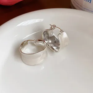 Dettaglio di orecchini a cerchio larghi minimalisti con finitura in smalto bianco crema