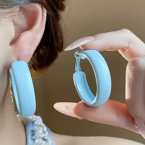 Close-up view of light blue spray-painted chunky hoop earrings with glossy finish